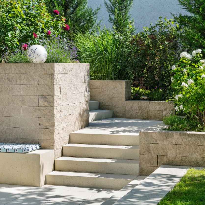 Natürlich angelegter Garten mit Mauer, Treppen und Sitzbänken aus Beton
