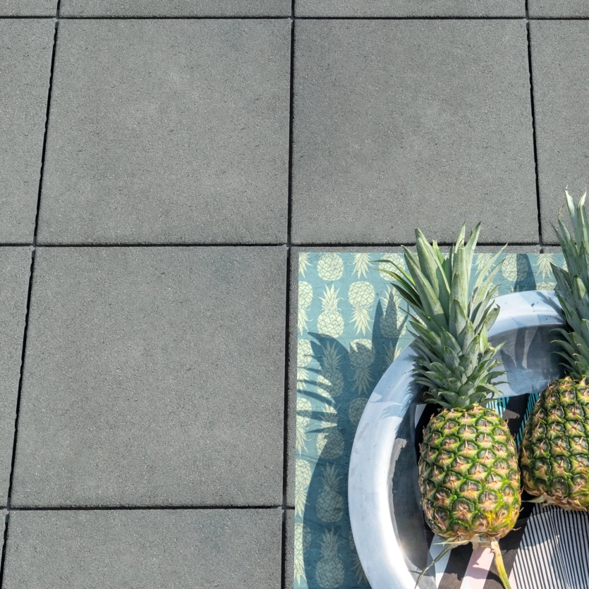 Bird's eye view of gray patio slabs with two pineapples in a bowl.