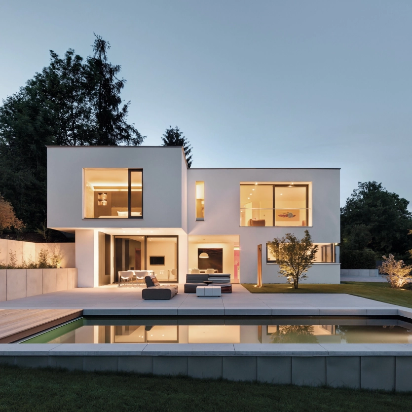 Illuminated villa with pool at night