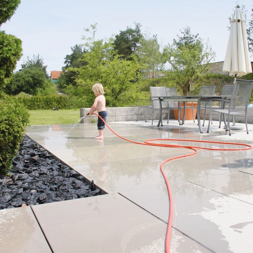 Child on patio with garden hose