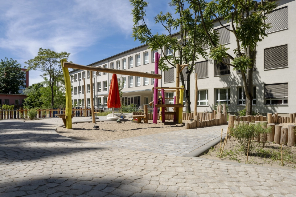 Außenbereich der Kita Wolkenschaf in Berlin mit naturnahen Spielgeräten und versickerungsfähigem GDM.BOLERO.