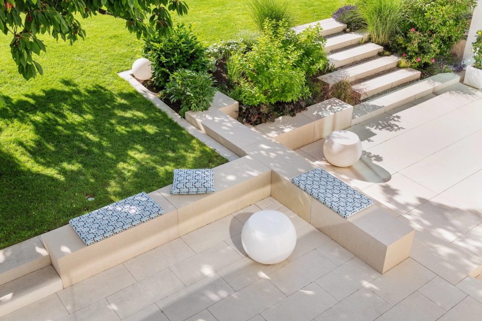 Private modern garden with sandstone-colored terrace and lots of greenery