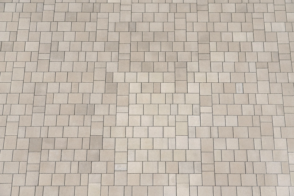 A paved area consisting of climate-positive concrete blocks laid in a wild bond. The ecological paving has a stainless steel shot-blasted, beige surface 