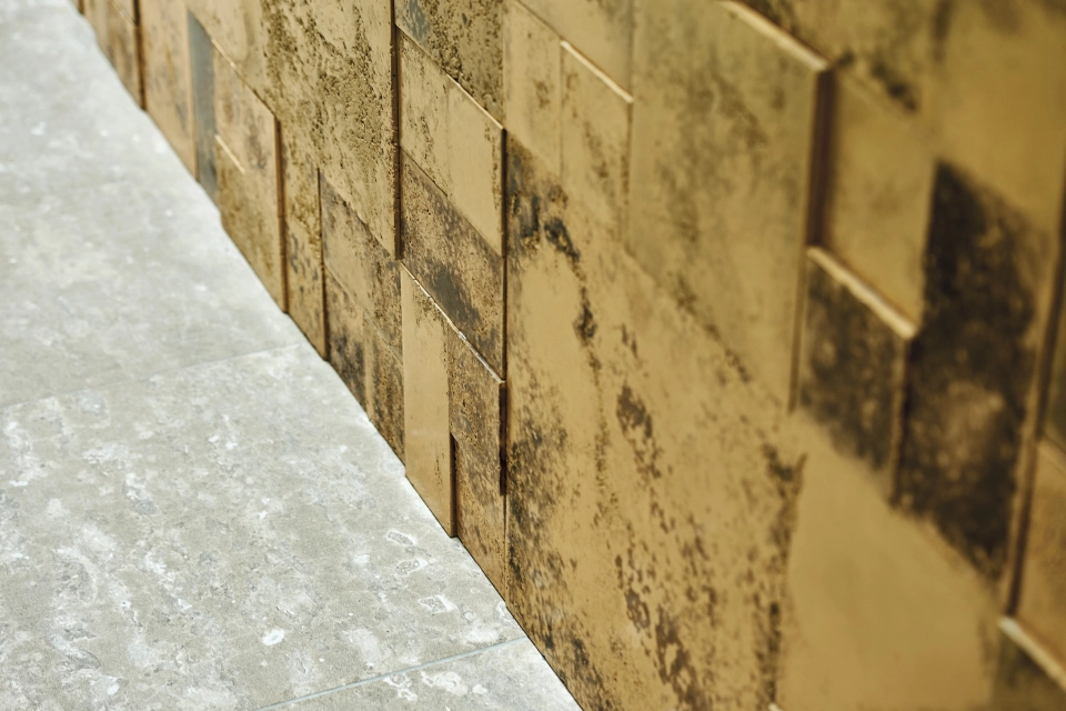 Wand aus gold- und bronzefarbenen Fliesen unterschiedlicher Dicke