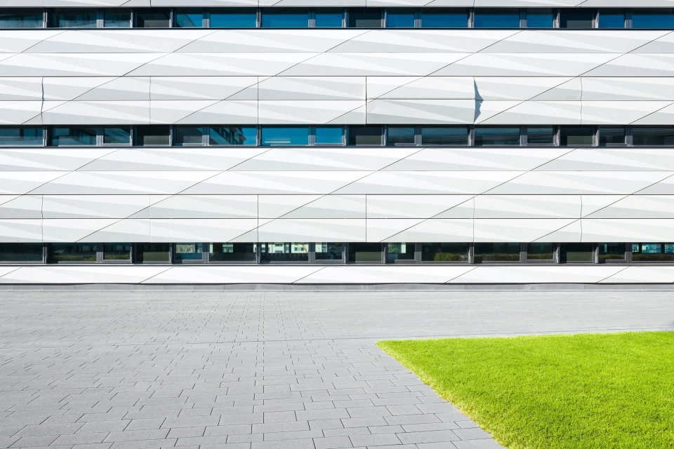 Spacious paved area in front of a white office building with a modern façade
