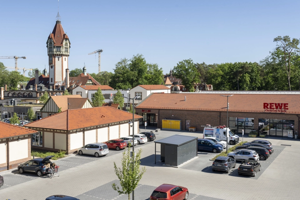 Parkplatzfläche aus GDM.KLIMASTEIN aBG am REWE Markt Christian Schulz mit Stellplätzen, Fahrgassen und umliegender Bebauung.