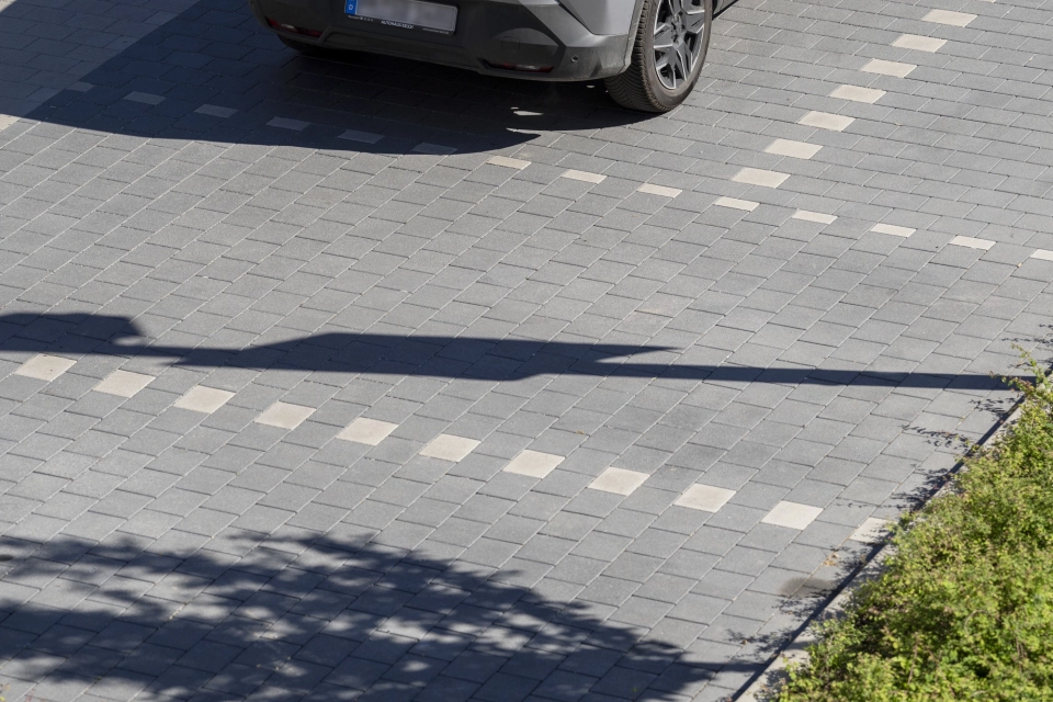 Fahrbahn aus GDM.KLIMASTEIN aBG mit markierten Stellplätzen und einem geparkten Fahrzeug auf dem Parkplatzgelände.