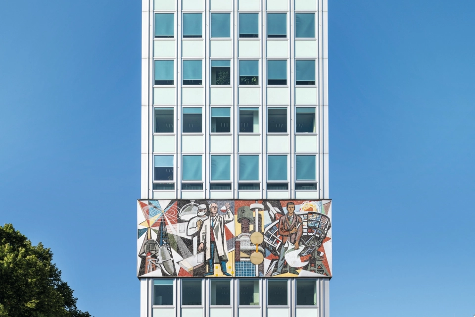 schmales Hochhaus mit Fensterfront und Mosaikelementen